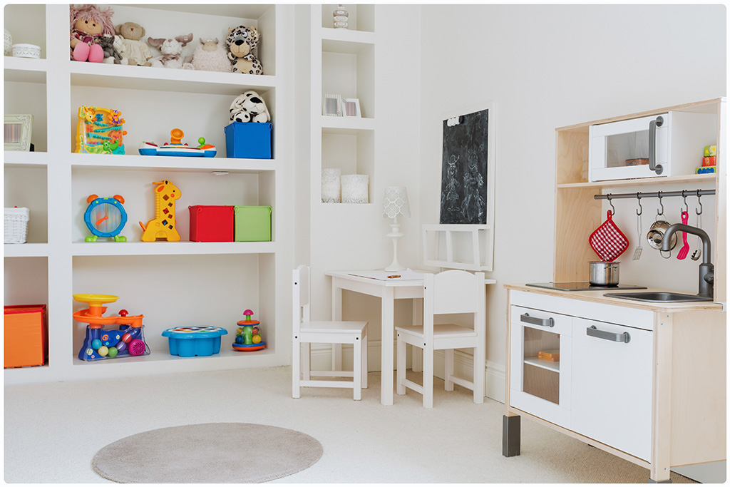Kids room designed so that toys are within reach and they can see all the toys they have. The color that predominates in the furniture of the room is white. It has a small table, chairs and kitchen of them size. Toys are distributed on shelves.